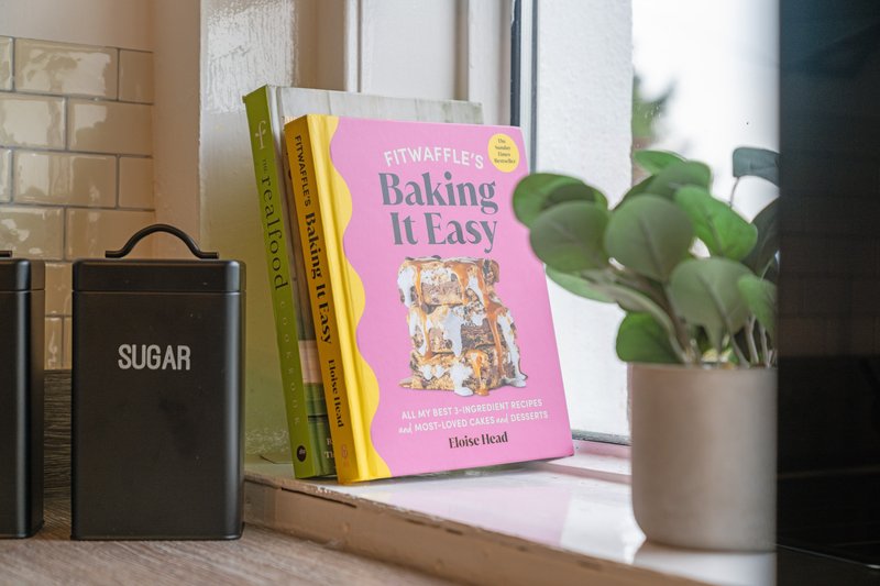 Kitchen windowsill with cookbooks, sugar container, potted plant and natural light