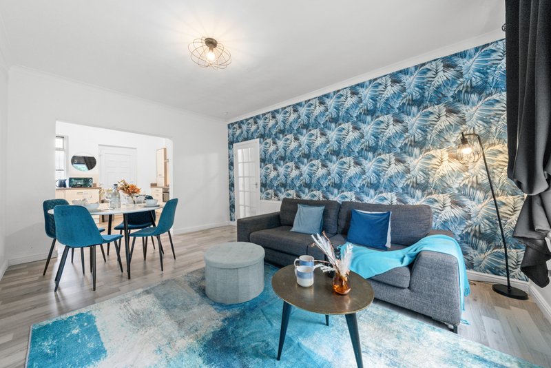 Modern open-plan living area with blue patterned wallpaper, sofa, dining table and chairs
