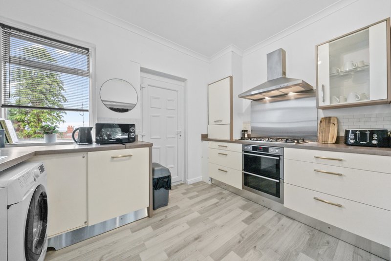 Modern kitchen with cream cabinets, gas range, washing machine, and window overlooking garden