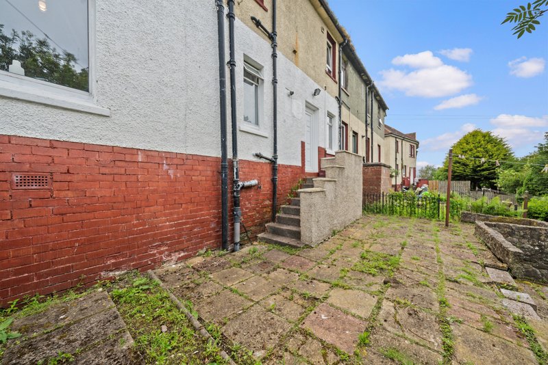 Brick terraced house exterior with red brick base, white rendered upper walls, concrete steps and paved courtyard