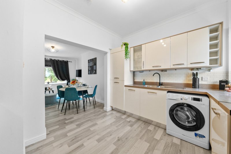Modern kitchen with cream cabinets, white appliances, and open-plan view to dining area
