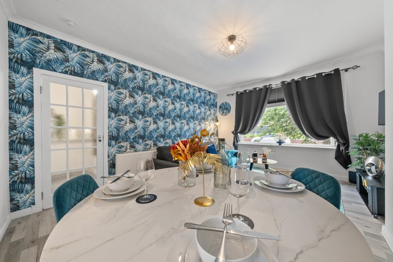 Modern dining room with marble table, teal chairs, blue wallpaper and black curtains
