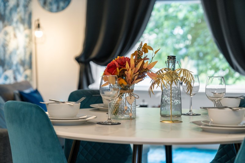 Dining table set with flowers, glasses, and place settings near window