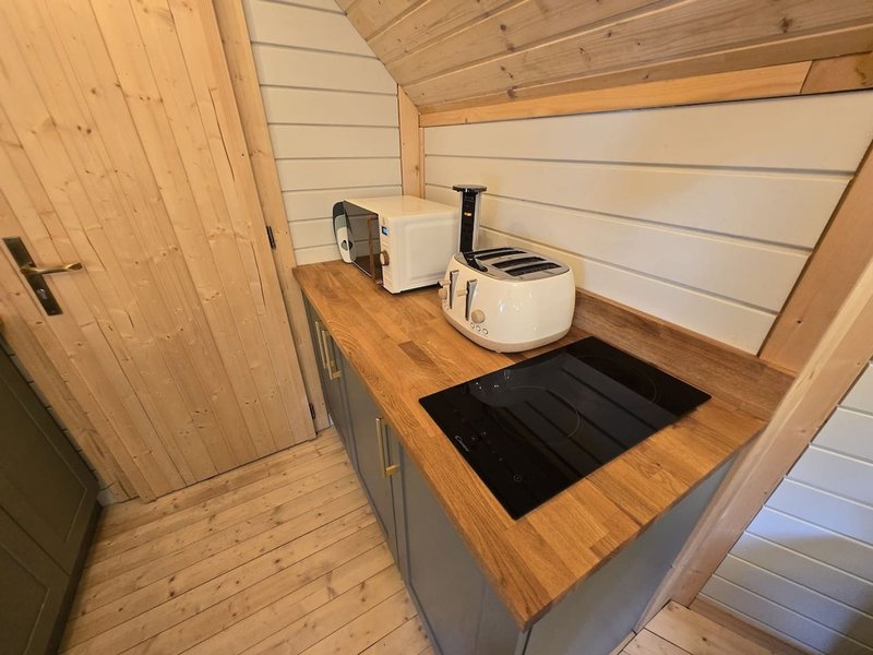 Compact kitchenette with wooden counter, white kettle, toaster and induction hob