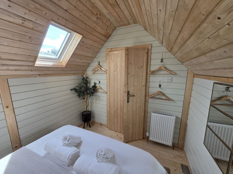 Attic bedroom with wooden beams, skylight, double bed and wooden wardrobe