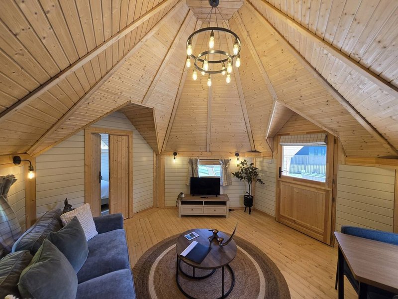 Spacious A-frame interior with wooden ceiling, fireplace, seating area and pendant lighting
