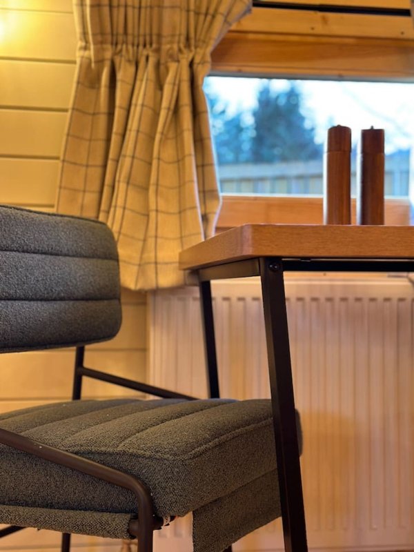 Modern chair and desk by window with yellow curtains and forest view