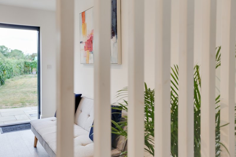 Modern interior with vertical striped partition, abstract wall art, potted plants, and view to garden
