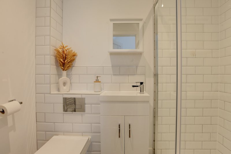 Modern bathroom with white subway tile, floating vanity, mirror, and glass shower enclosure