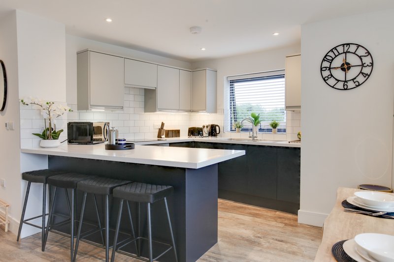 Modern kitchen with white cabinetry, dark island, bar seating, and dining area
