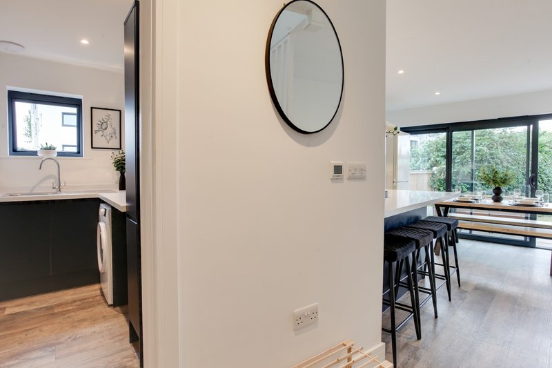 Modern kitchen and dining area with round mirror, bar seating, and garden views