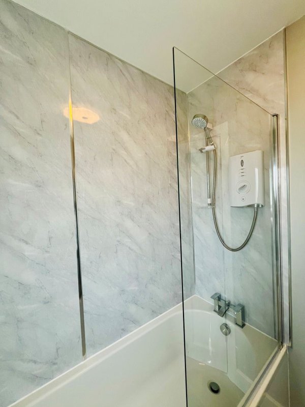 Modern bathroom with marble-tiled shower enclosure, white bath and chrome fixtures