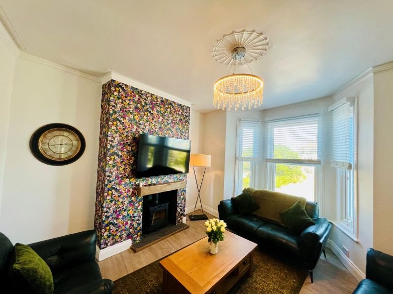 Modern living room with black sofa, wooden coffee table, fireplace with patterned accent wall and wall-mounted TV