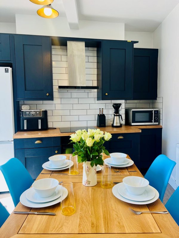 Modern kitchen with blue cabinetry, white subway tiles, and wooden dining table set for four