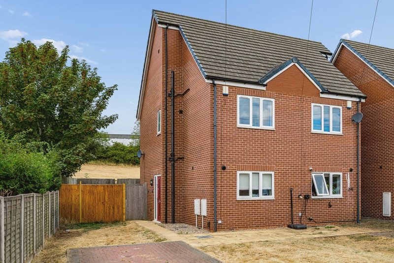 Red brick detached house with driveway, wooden fence, and front garden