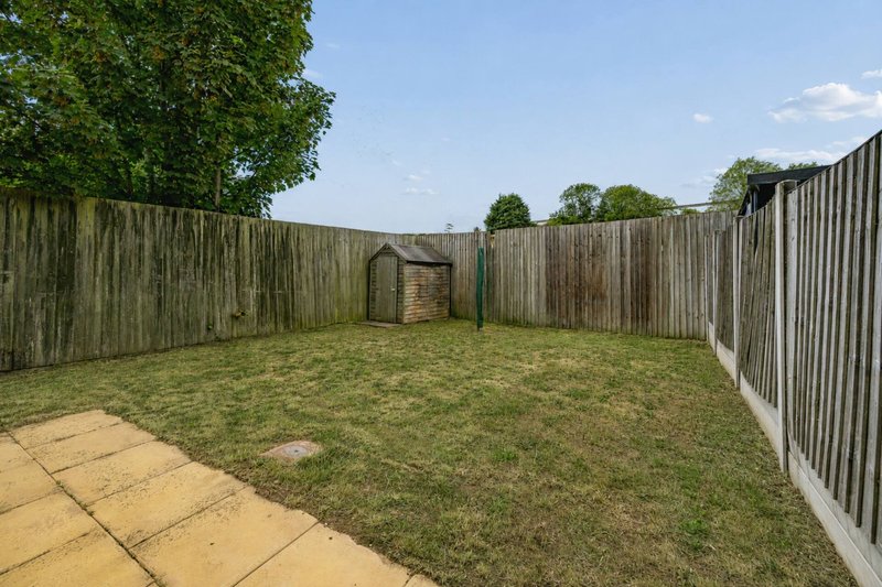 Enclosed garden with paved patio, lawn, wooden fencing and small shed