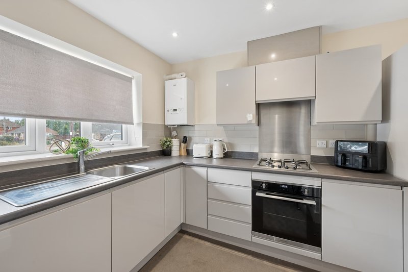 Modern kitchen with white cabinets, stainless steel appliances, and window overlooking garden