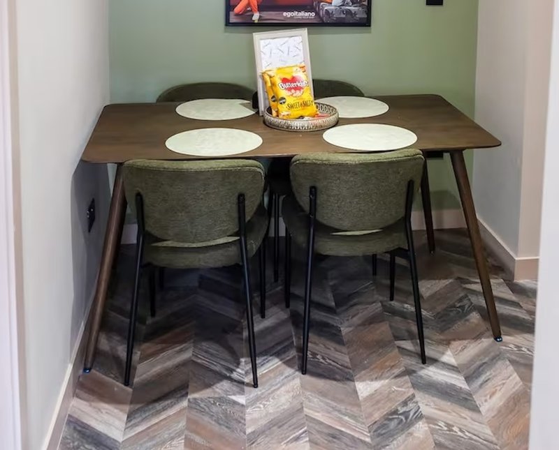 Dining table with four chairs, place settings, and packaged food item centerpiece