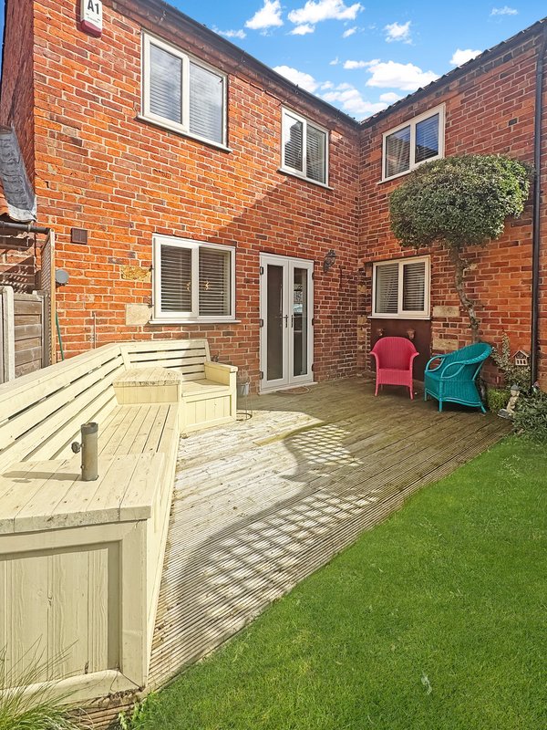 Brick courtyard with wooden decking, patio seating area, garden furniture and lawn