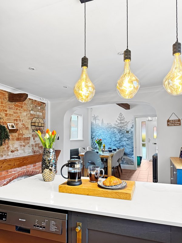Modern kitchen with island, pendant lights, brick feature wall and garden view