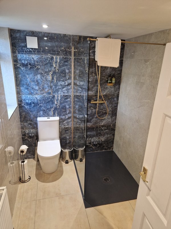 Modern bathroom with walk-in shower, toilet, and beige tile flooring throughout