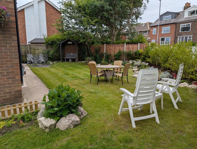 Spacious garden with lawn, outdoor seating areas, patio furniture and brick house