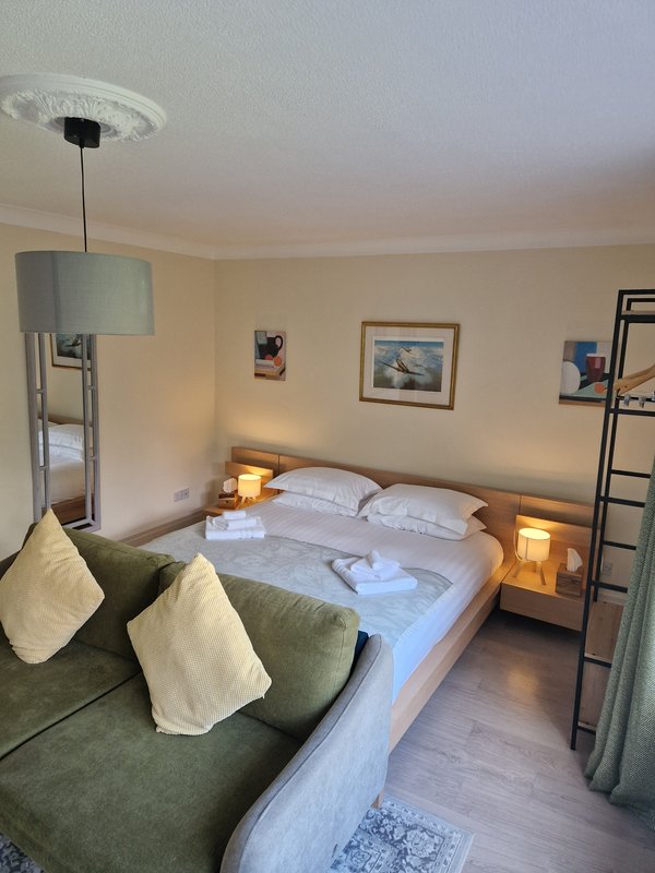 Bedroom with double bed, bedside lamps, green armchair, pendant light and wall art