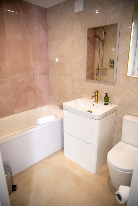 Modern bathroom with walk-in shower, white vanity unit, toilet and mirror