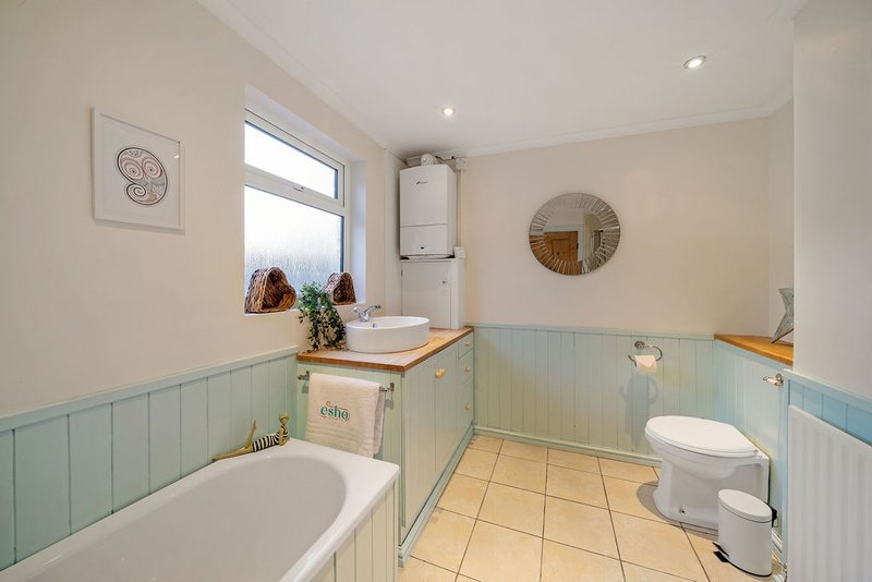 Bathroom with freestanding bathtub, toilet, pedestal sink, and pale green panelling