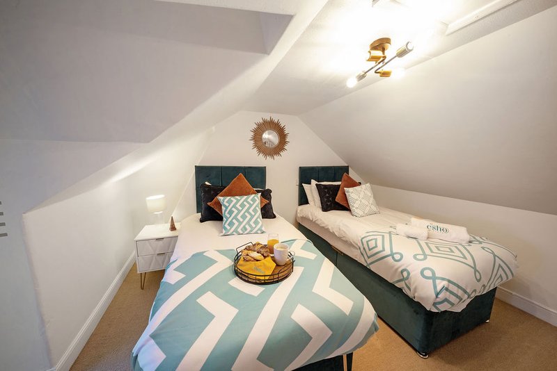 Bright attic bedroom with two single beds, geometric bedding, and decorative wall ornaments