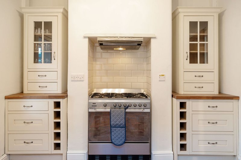 Modern kitchen with cream cabinetry, stainless steel range cooker and subway tile backsplash