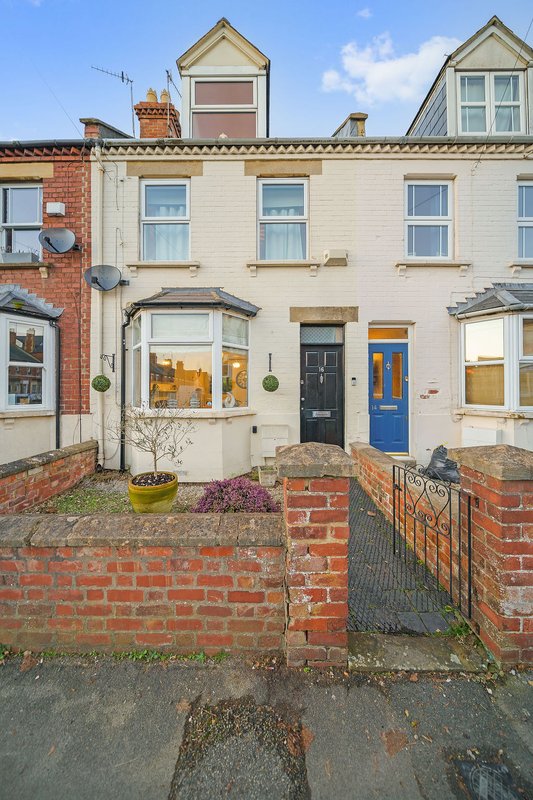Cream and brick terraced house with blue door, bay windows and front garden