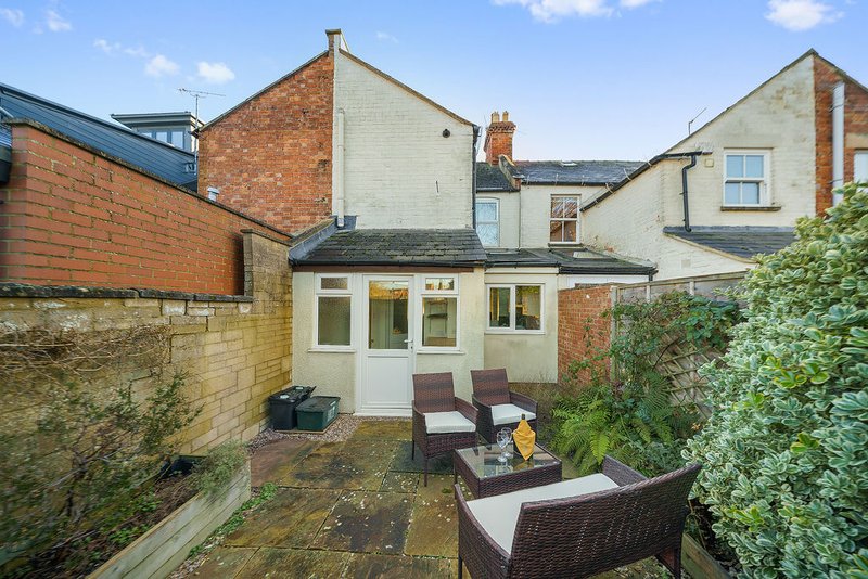 Brick townhouse with patio seating area, rattan furniture and climbing ivy
