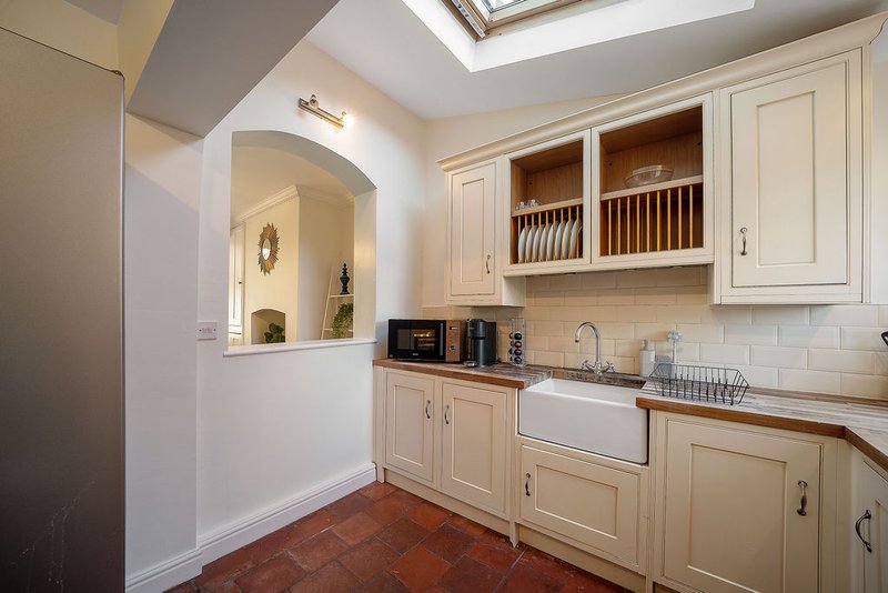 Cream kitchen with white subway tile, farmhouse sink, open shelving and skylight