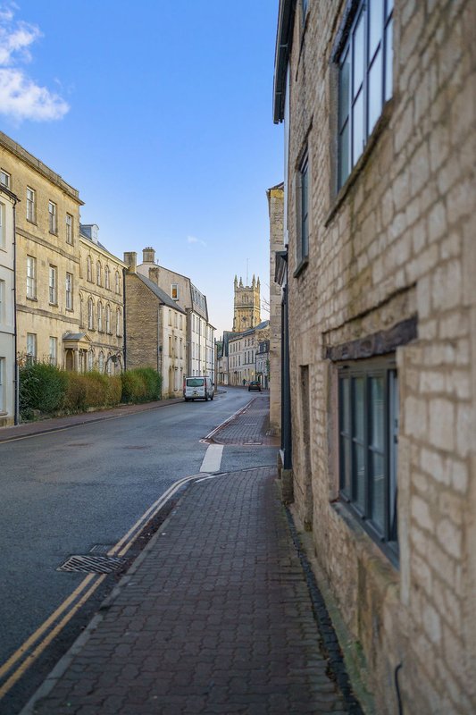 Street view of stone terraced buildings with church tower visible in distance