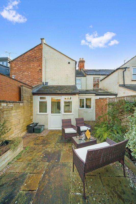 Brick house with patio area, garden furniture, and rear extension with white doors