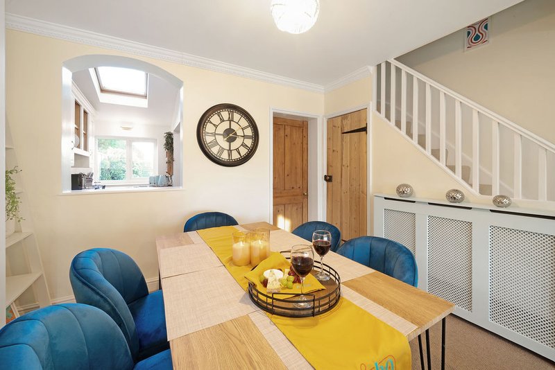 Bright dining room with wooden table, blue chairs, yellow table runner and wall clock
