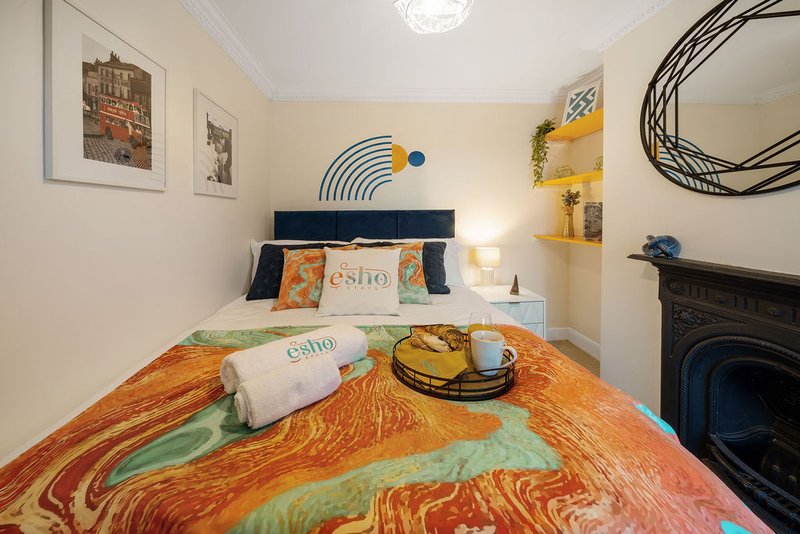 Cozy bedroom with colorful bedding, pillows, wall art, and decorative elements