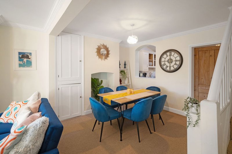 Open-plan living and dining space with blue sofa, yellow dining table, wall clock and modern decor