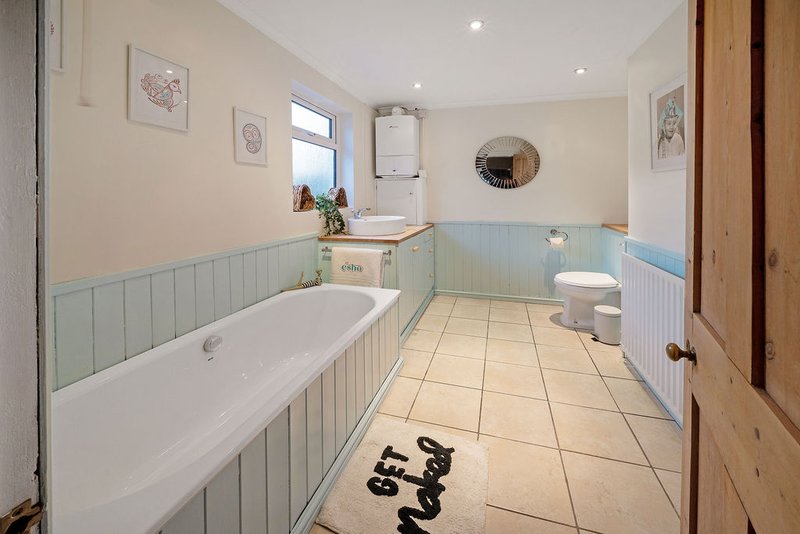 Bathroom with bathtub, toilet, sink, tiled floor, and panelled walls