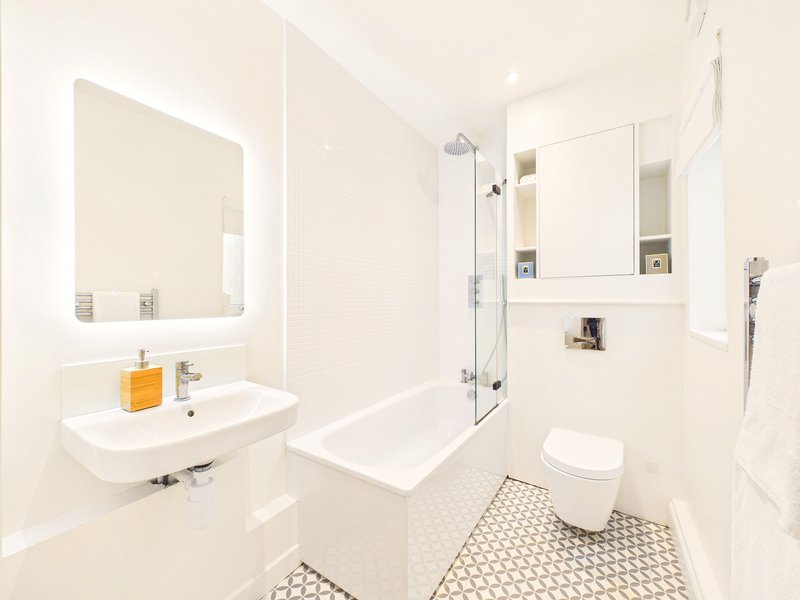 Modern white bathroom with floating sink, mirror, walk-in shower and toilet