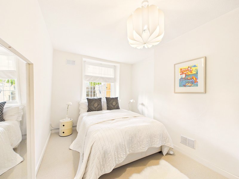 Bright bedroom with double bed, cream bedding, pendant light, and framed artwork on wall