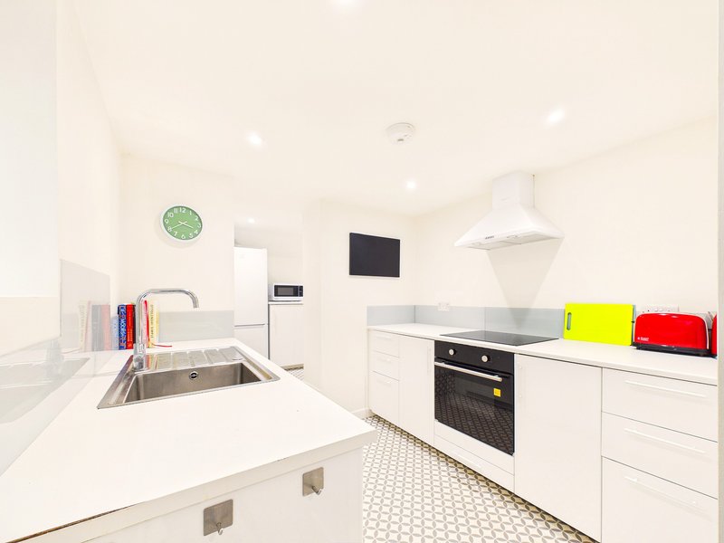 Modern white kitchen with stainless steel sink, built-in oven, and bright counter space