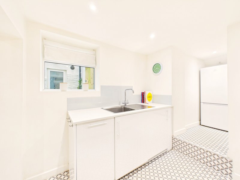 Clean white laundry room with sink, cabinets, window and tiled floor