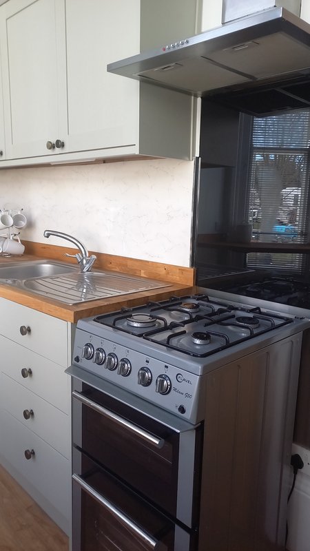 Kitchen with white cabinetry, wooden worktop, gas range cooker and extractor hood