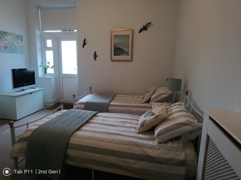 Bright bedroom with two single beds, striped bedding, small TV, and wall decorations
