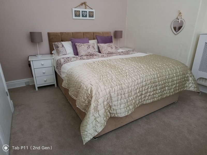 Bedroom with double bed, upholstered headboard, bedside tables and wall decor