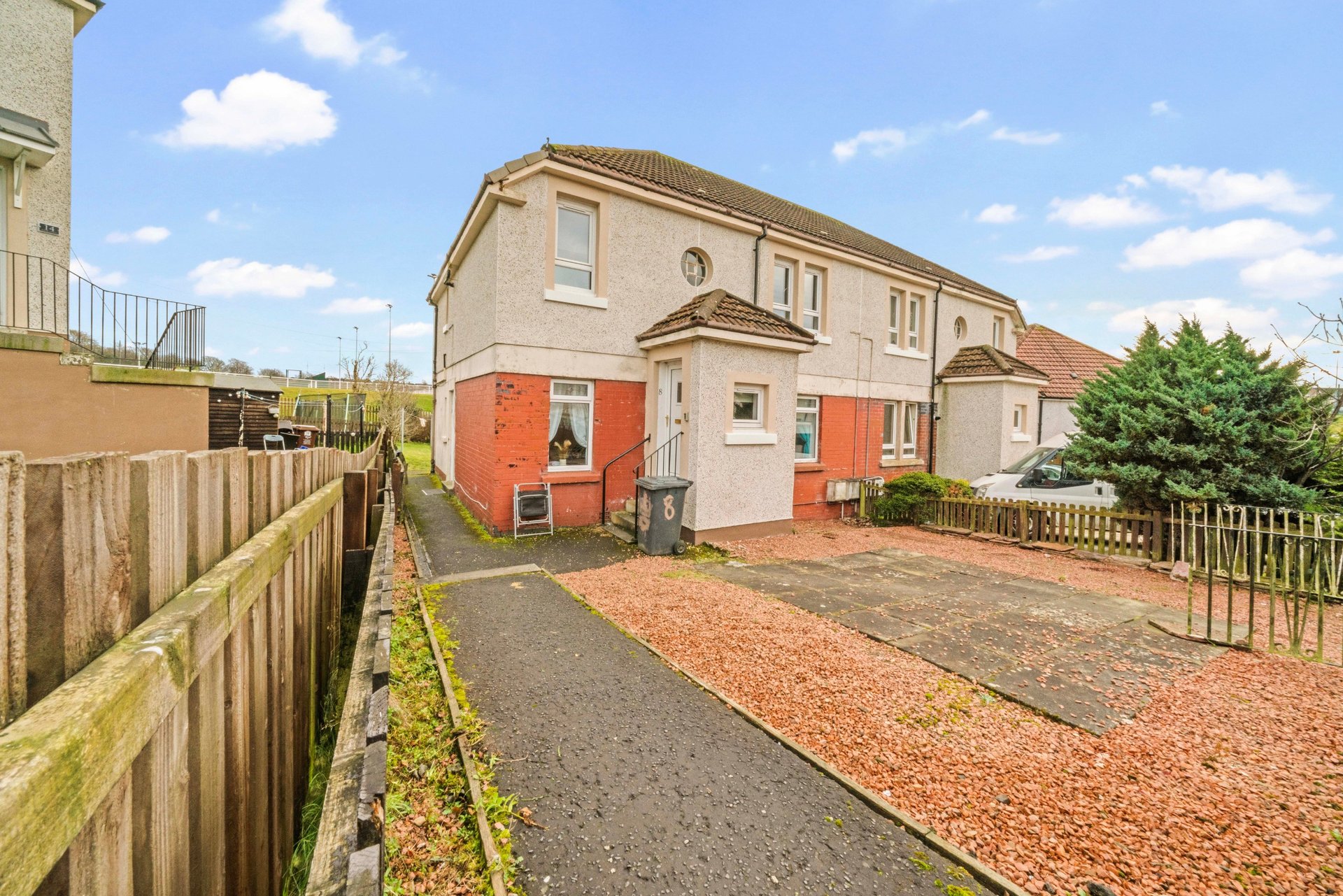 Semi-detached house with red brick lower section, driveway, and front garden fencing