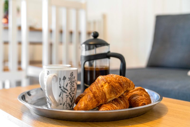 Coffee table with croissants, mug, and French press in modern living room