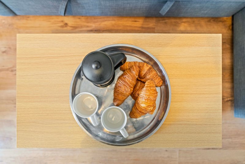 Overhead view of wooden table with breakfast tray containing croissants, teapot and cups